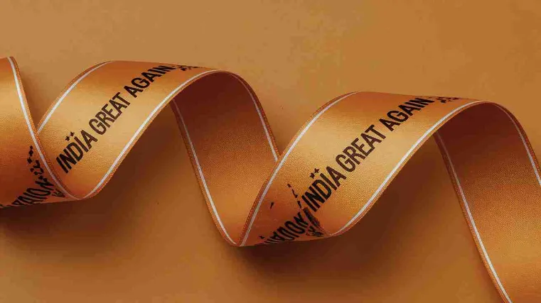 A Möbius strip made of saffron-colored ribbon, with "India Great Again" printed repeatedly along its length